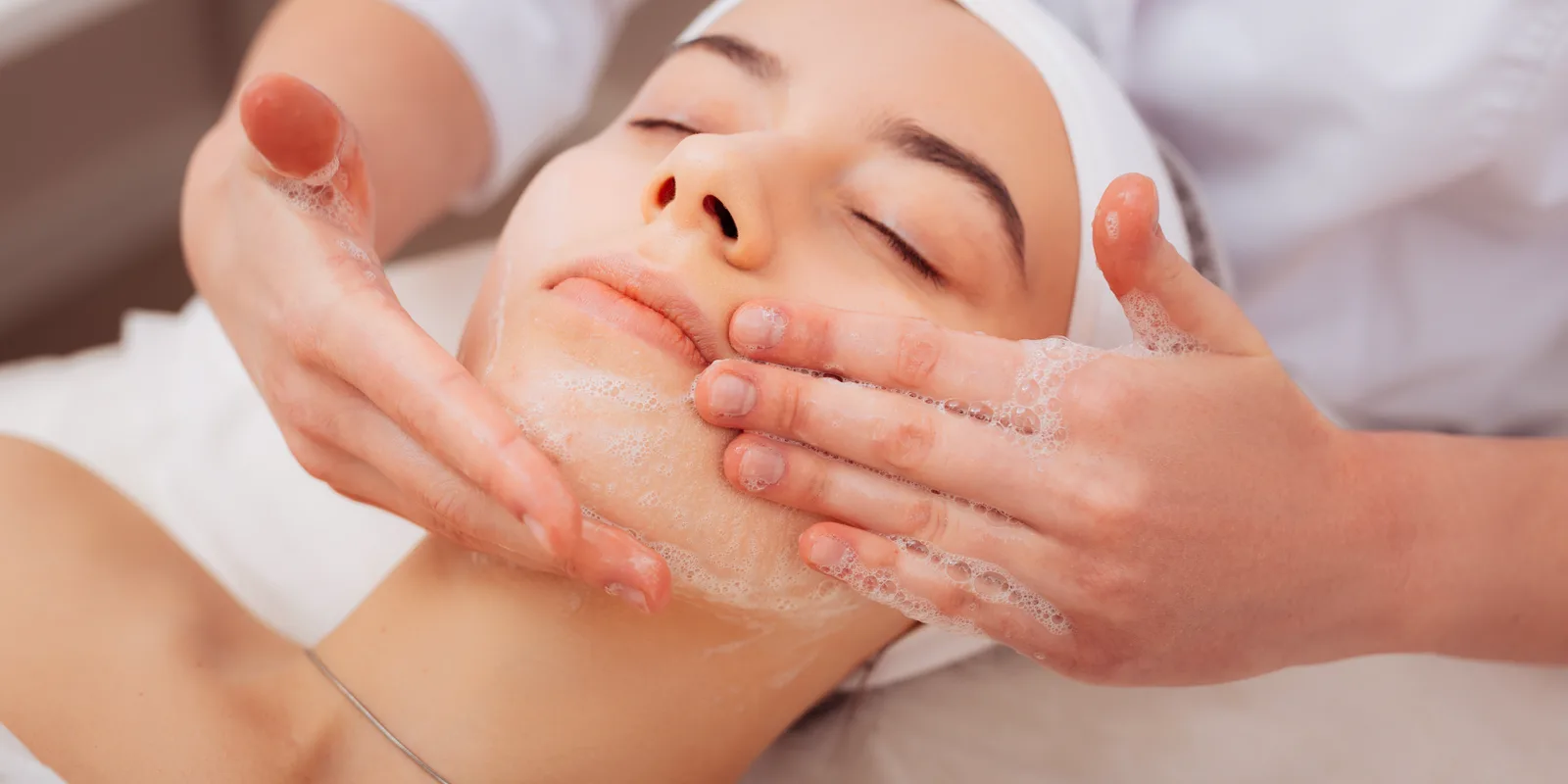 Licensed aesthetician performing a cleansing facial treatment